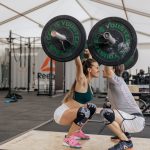 A couple lifting weights together in a gym, promoting fitness and teamwork.